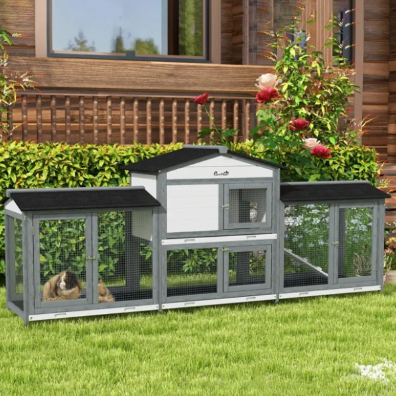 Large outdoor rabbit hutch setup in the garden with guinea pigs resting inside the enclosure.

