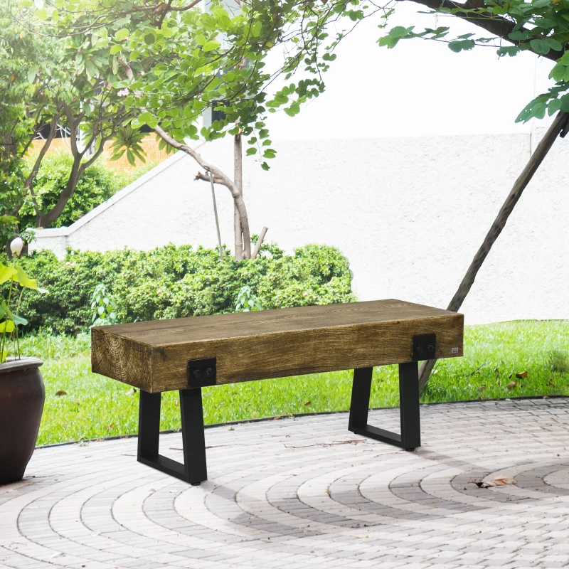 Rustic wooden outdoor bench on stone patio under trees.