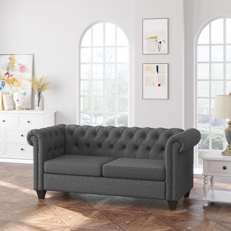 Dark grey tufted loveseat in bright living room with arched windows.