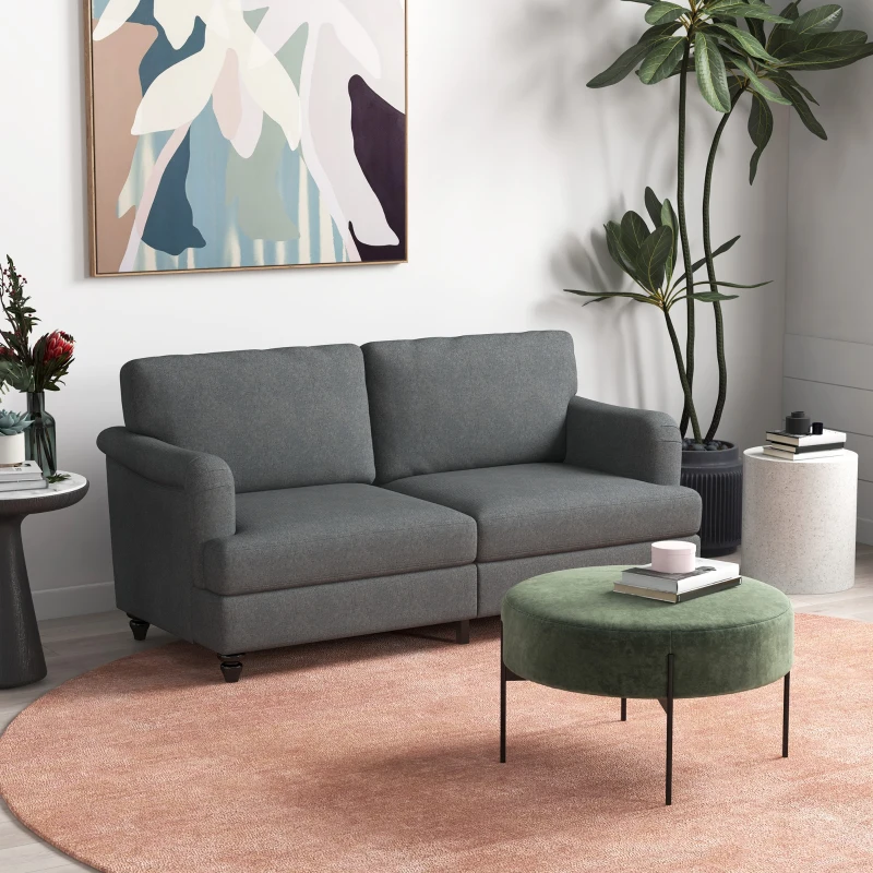 Dark grey three-seater sofa with green ottoman and plants.