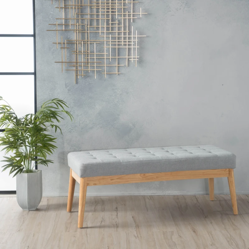 Light grey fabric bench with wooden legs near decorative wall art.