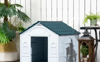 dog house placed outdoors on a wooden deck with plants and lanterns nearby.