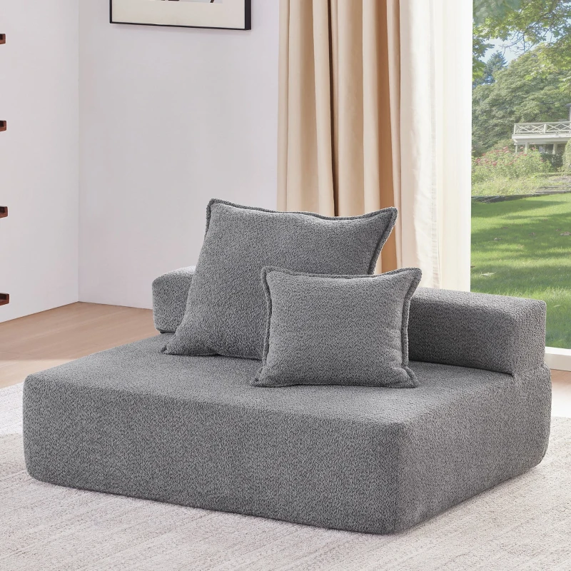 Grey plush single-seat floor sofa with two cushions near window.