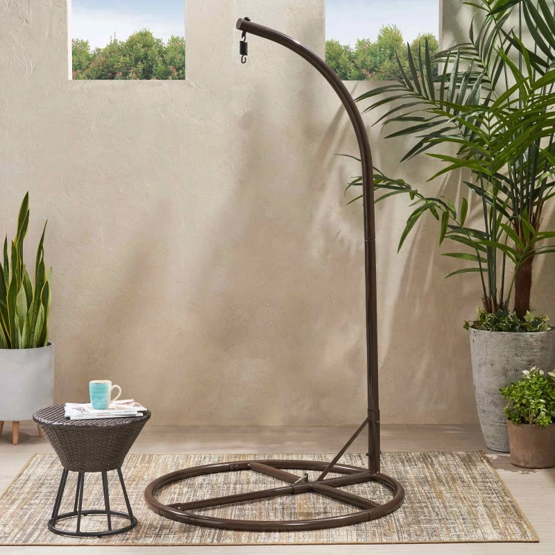 Brown curved metal hammock stand beside small table and plants.