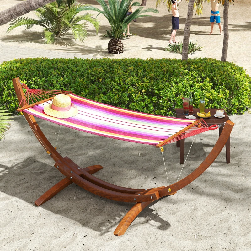 Colourful striped hammock with wooden stand on sandy beach.