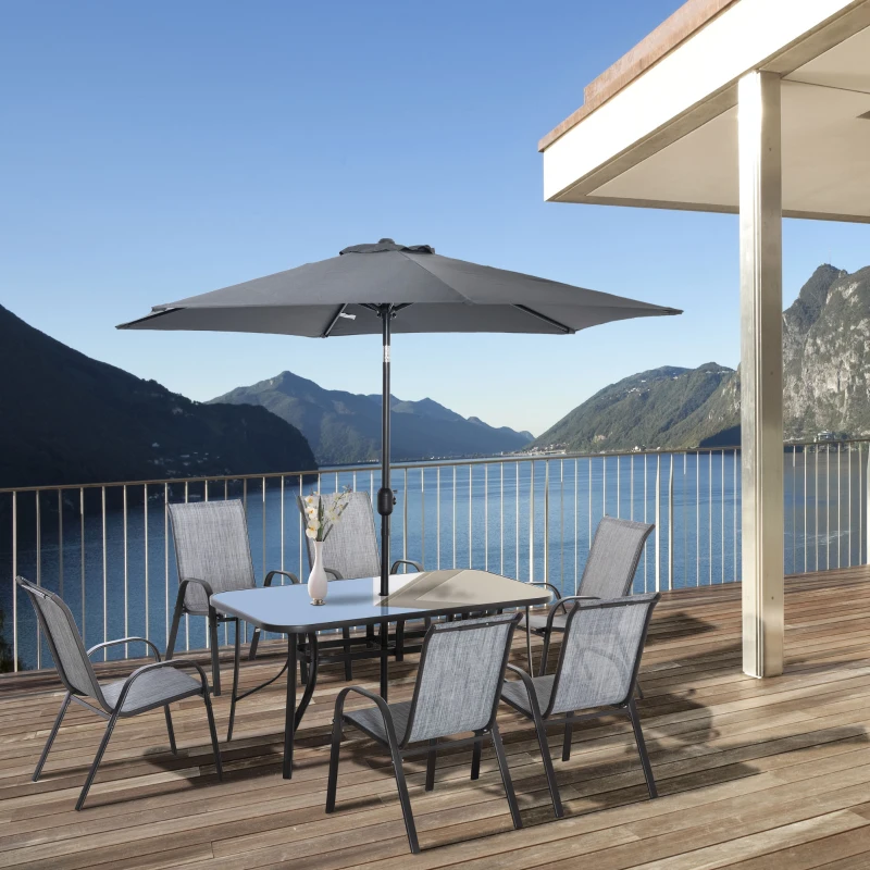 Metal outdoor dining set with six chairs and gray umbrella on a balcony overlooking mountains and lake.