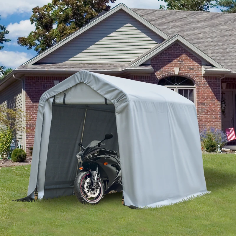 Small gray carport canopy housing motorcycle near brick house lawn.
