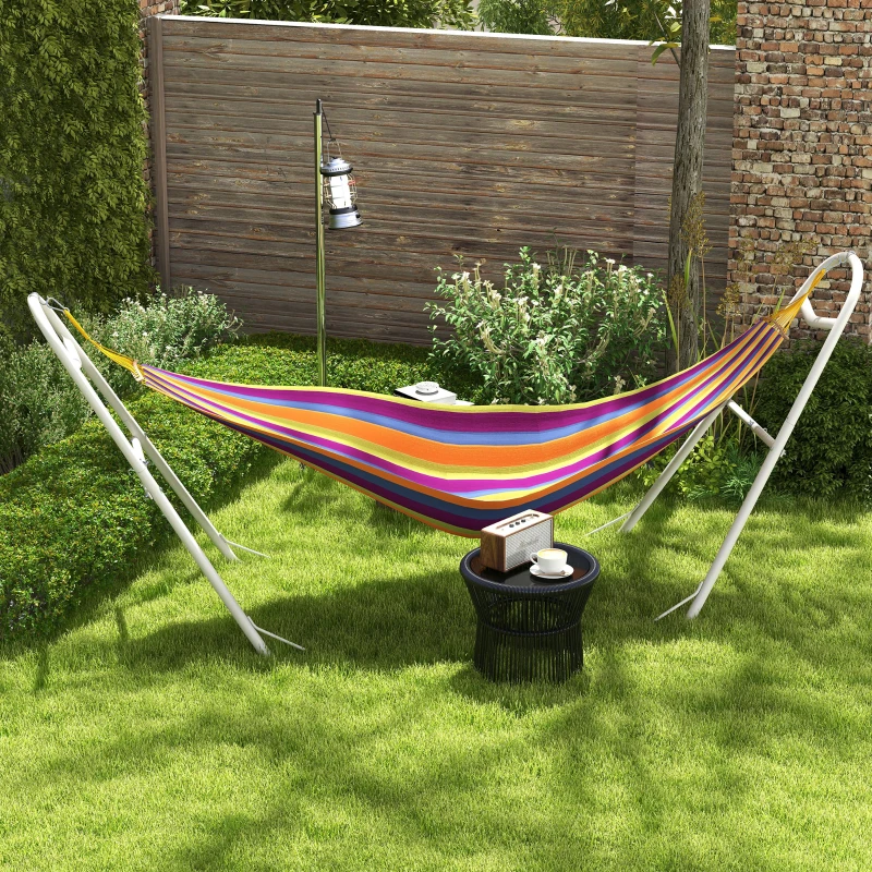 Striped hammock on white steel stand set in green garden.