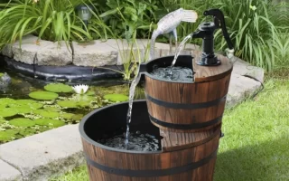 two-tier wooden barrel garden fountain with flowing water displayed beside a backyard pond.