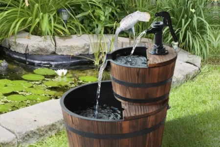 two-tier wooden barrel garden fountain with flowing water displayed beside a backyard pond.