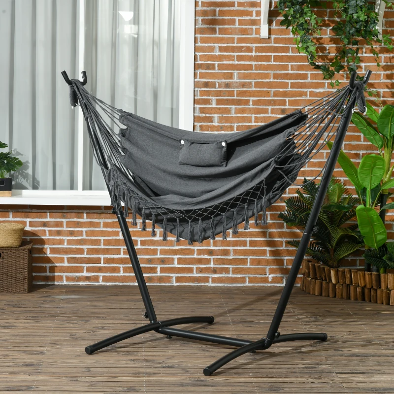 Grey hammock with pillow on black U-shaped stand near brick wall.