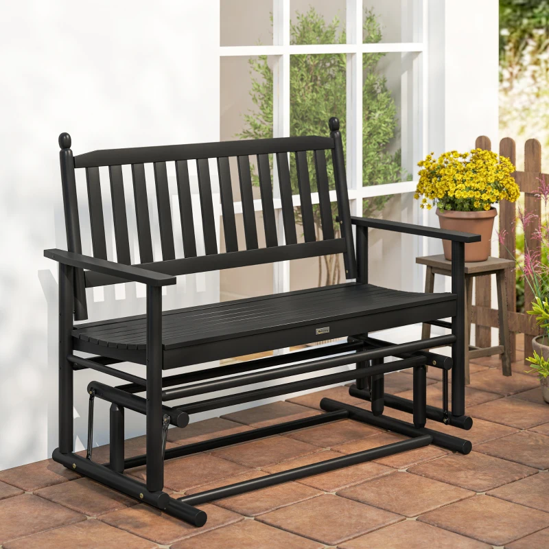 Black wooden outdoor glider bench with slatted backrest placed near the window and potted flowers.