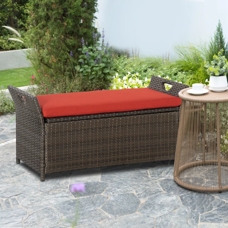Brown wicker patio bench with red cushion beside round table.
