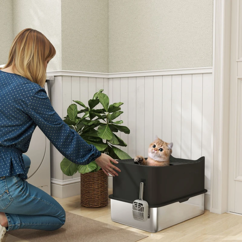 Woman interacting with cat in black and silver open litter box.