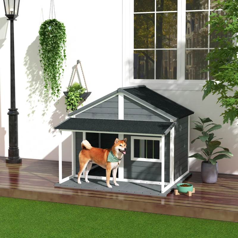 medium dog standing on the porch of a grey wooden outdoor cabin-style dog house.