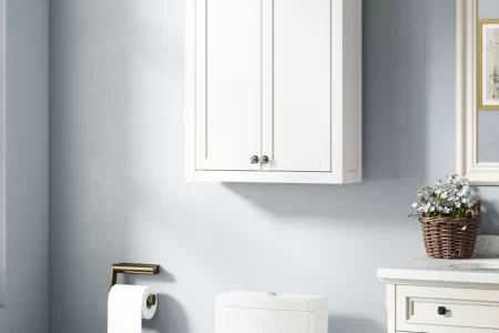White wall-mounted bathroom cabinet with double doors above toilet and sink.