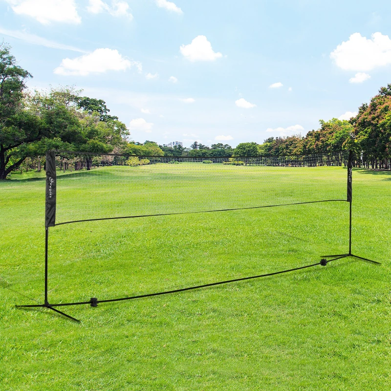 Portable badminton net set placed on open grassy field.