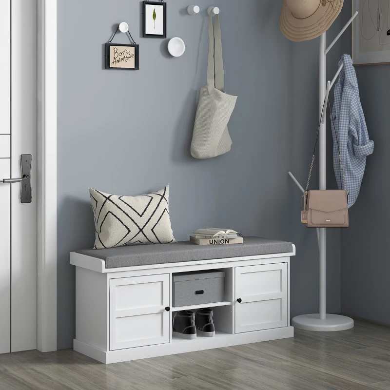 White hallway storage bench with grey cushion and shoe cubbies.