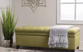 Green upholstered storage bench with blanket in modern room.