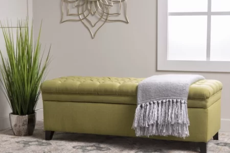 Green upholstered storage bench with blanket in modern room.