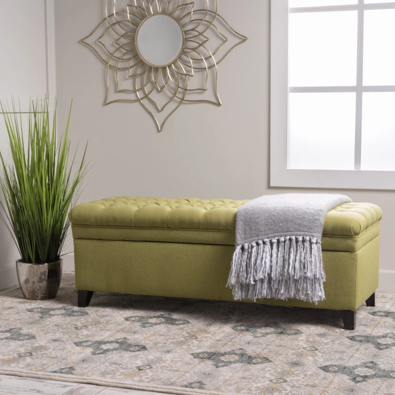 Green upholstered storage bench with blanket in modern room.