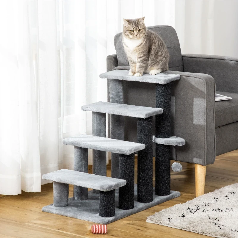 Grey cat sitting on a multi-step cat tree positioned beside a grey sofa.
