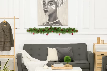 Festive wall art framed with garlands displayed above a modern sofa in a decorated living room.