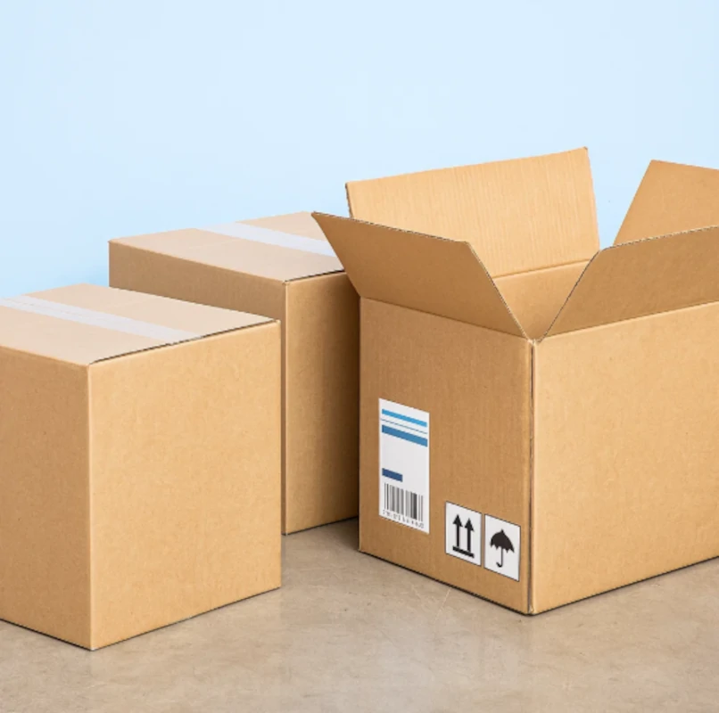Three clean cardboard boxes, including one open box, arranged on a floor.
