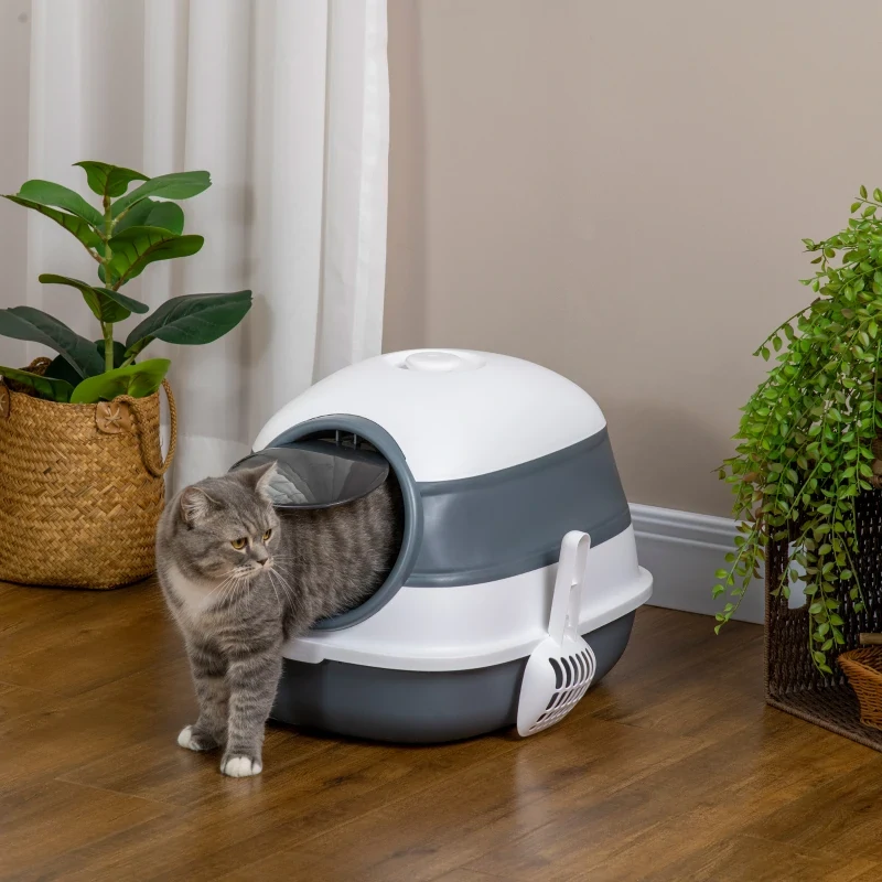 Gray cat exiting a dome-style litter box in a cozy indoor corner.