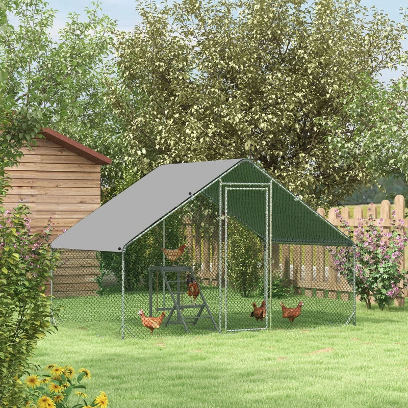 Large walk-in metal chicken run with a peaked gray shelter roof in a green backyard setting.
