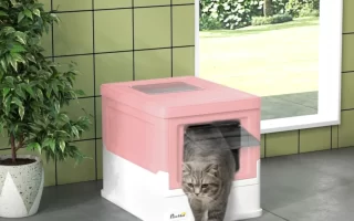 Cat exiting a pink covered litter box placed near a window and indoor plant.